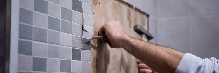 professional worker remove demolish old tiles in a bathroom with hammer and chisel